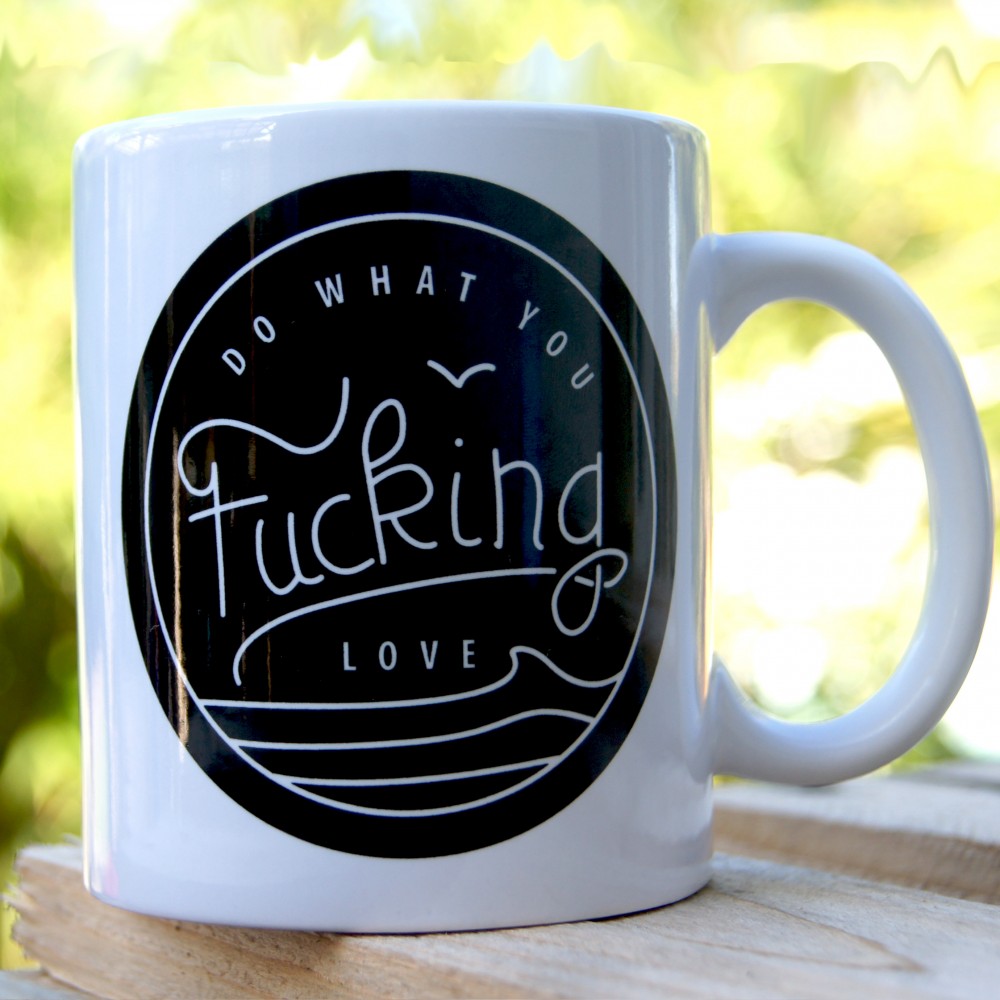 Tasse Mug KDC-Surfwear "Do What You Fucking Love" avec texte audacieux, blanche avec poignée noire, vue de face.